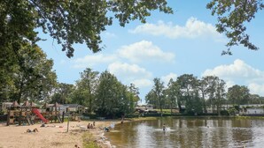 A lakeside area with a sandy beach, a playground with a slide, and a pavilion. - Gorgeous home in Merksplas (Merksplas)