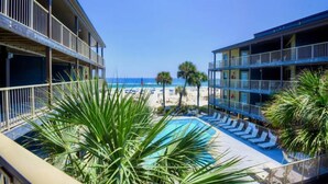 A hotel with a pool, palm trees, and a view of the beach. - Sandpiper 7-C  ON THE BEACH - Heated Pool - Smart TVs (Gulf Shores)