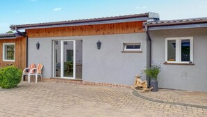 Un immeuble résidentiel à la façade grise, aux ornements en bois et à l’allée pavée.
