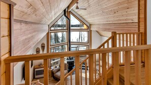 Un interior de madera con techo alto, ventanas amplias y una escalera.
