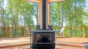A cozy cabin with a large window and a wood-burning stove.