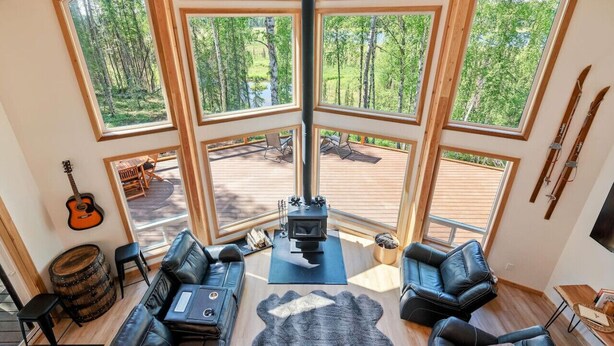 A cozy cabin interior with a large wooden deck, a fireplace, and a view of a forest.
