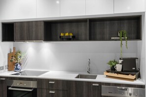 A modern kitchen with a built-in oven, a stainless steel sink, and a coffee machine on the countertop. - Luxurious Fitzroy Street Getaway (St Kilda)