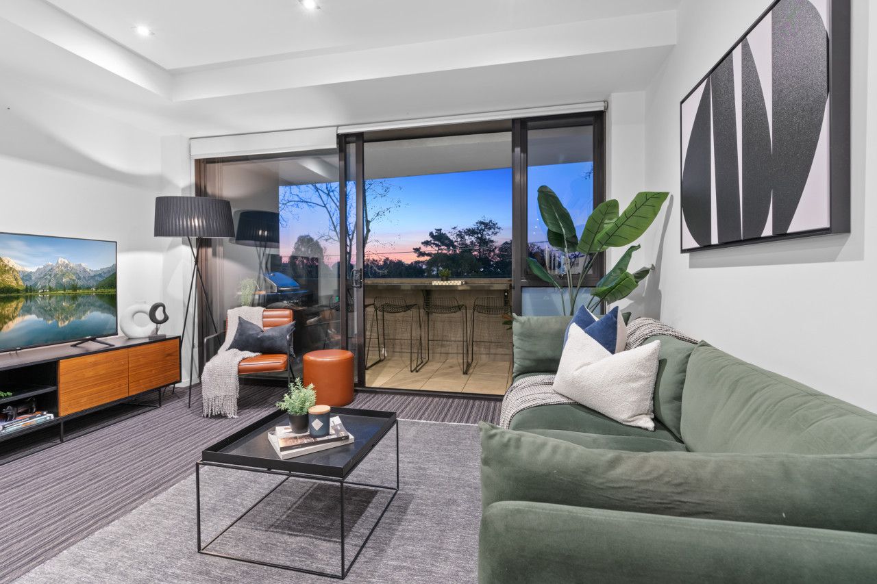 A modern living room with a green sofa, a coffee table, a TV, and a sliding glass door leading to an outdoor area.