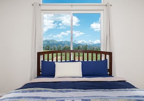 A bed with a wooden headboard, white curtains, and a view of mountains through a window. - Modern Home with Panoramic Teton Views (Tetonia)