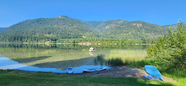 Un lac paisible, avec des bateaux, et une vue dégagée sur des montagnes boisées.