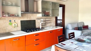 A modern kitchen with orange cabinets, a gas stove, and a glass-fronted upper cabinet. - SE123 - Marzocca, three-room apartment 300 meters from the sea (Marzocca)