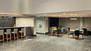 A modern conference room with a marble floor, round tables with chairs, and a central light fixture. - Melhores Flats -Conforto pertinho do mar (João Pessoa)
