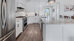 A modern kitchen with white cabinetry, stainless steel appliances, and a large island.