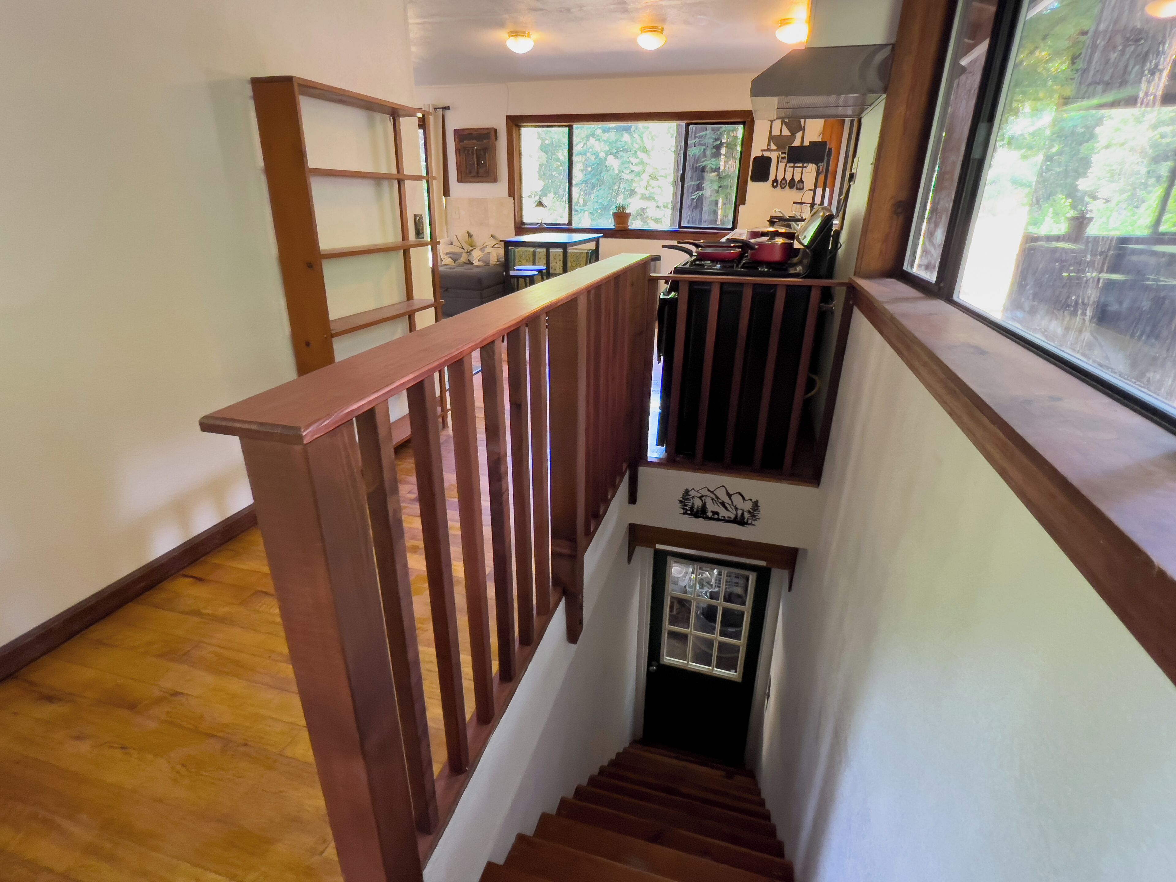 Una escalera de madera que conduce a un segundo piso, donde se ve un área de cocina al fondo.