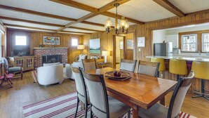 A spacious living room with a wooden dining table, comfortable seating, a fireplace, and a kitchen area visible through an open doorway. - Center Hill Couples Retreat Cabin: Lake View, Deck (Sparta)
