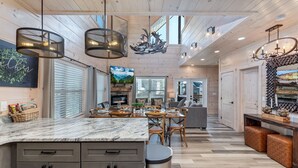 Un'ampia cucina con isola in marmo, mobili in legno e illuminazione a sospensione.