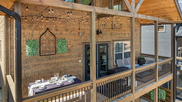 Una terrazza in legno a più livelli con luci decorative, un'area pranzo e vista sul paesaggio circostante.