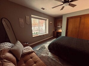 A bedroom with a bed, a window, a desk, and a wardrobe.