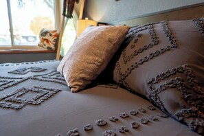 Ein Bett mit einer gemusterten Bettdecke und zwei Kissen, eines mit strukturierter Oberfläche und das andere mit floralem Muster.