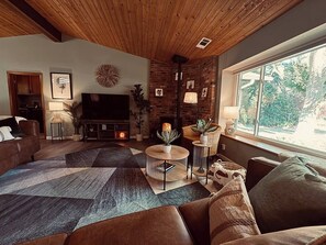 Una sala de estar acogedora con chimenea, asientos cómodos y un ventanal con vistas al exterior.