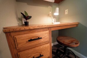 A wooden desk with a drawer and a stool.