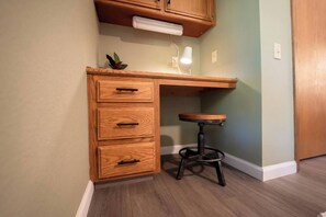 Ein Eckzimmer mit Schreibtisch, Hocker und Wandleuchte.