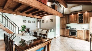A spacious kitchen with wooden cabinets, a dining area with a wooden table and chairs, and a staircase leading to an upper level. - Lake Frame - MyHomeinComo (Blevio)