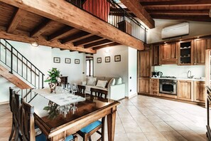 A spacious kitchen with wooden cabinets, a dining area with a wooden table and chairs, and a staircase leading to an upper level. - Lake Frame - MyHomeinComo (Blevio)