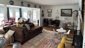 A cozy living room with a brown sofa, a patterned rug, and a variety of chairs and tables. - Lake house 35 from Auburn and Ft. Benning (Salem)