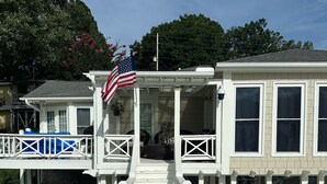 A wooden deck leading to a house with a porch, a flag, and a view of the surrounding area. - Lake house 35 from Auburn and Ft. Benning (Salem)