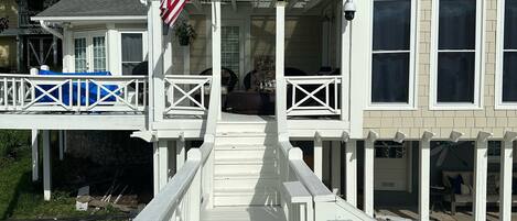 A wooden deck leading to a house with a porch, a flag, and a view of the surrounding area.