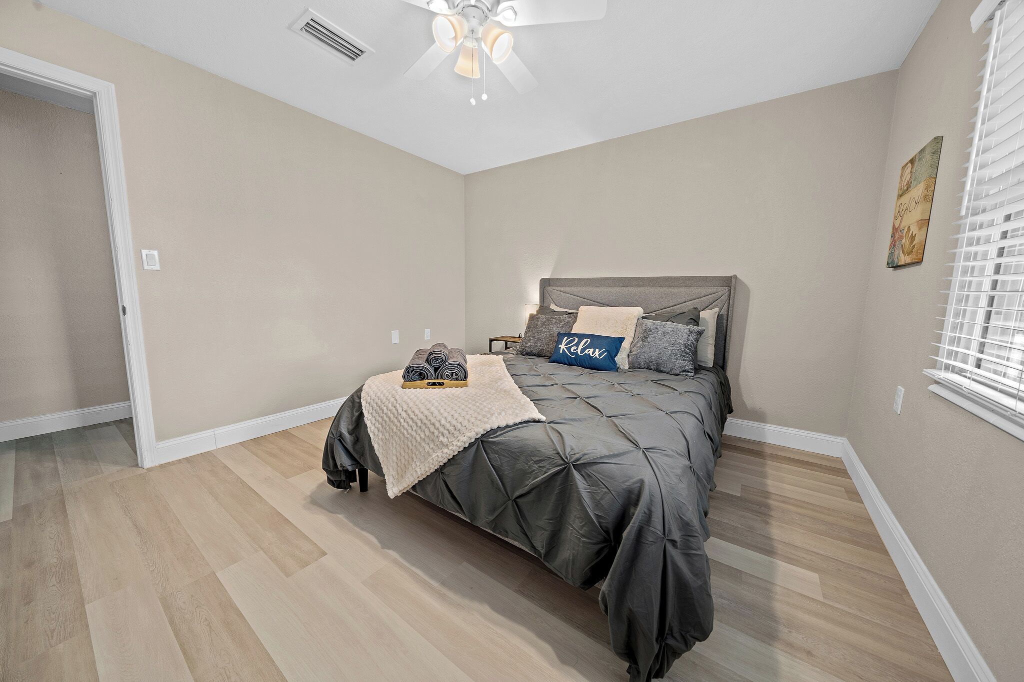 A bedroom with a bed, a ceiling fan, and a window with blinds.