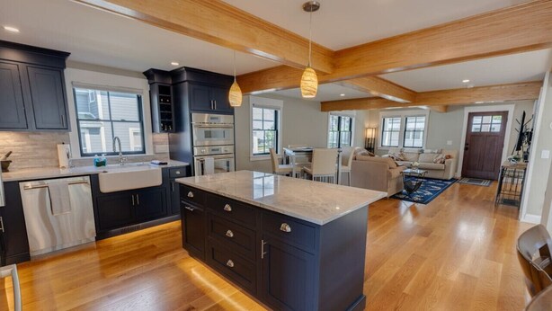 A modern kitchen with dark cabinets, a large island, and wooden flooring. - Luxury House in Lincoln (Lincoln)