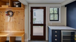A room with a wooden bench, a door with a window, a small window, and a cabinet with drawers. - Luxury House in Lincoln (Lincoln)