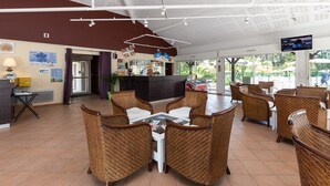 Un restaurante con mobiliario de mimbre, un televisor y vistas al exterior.
