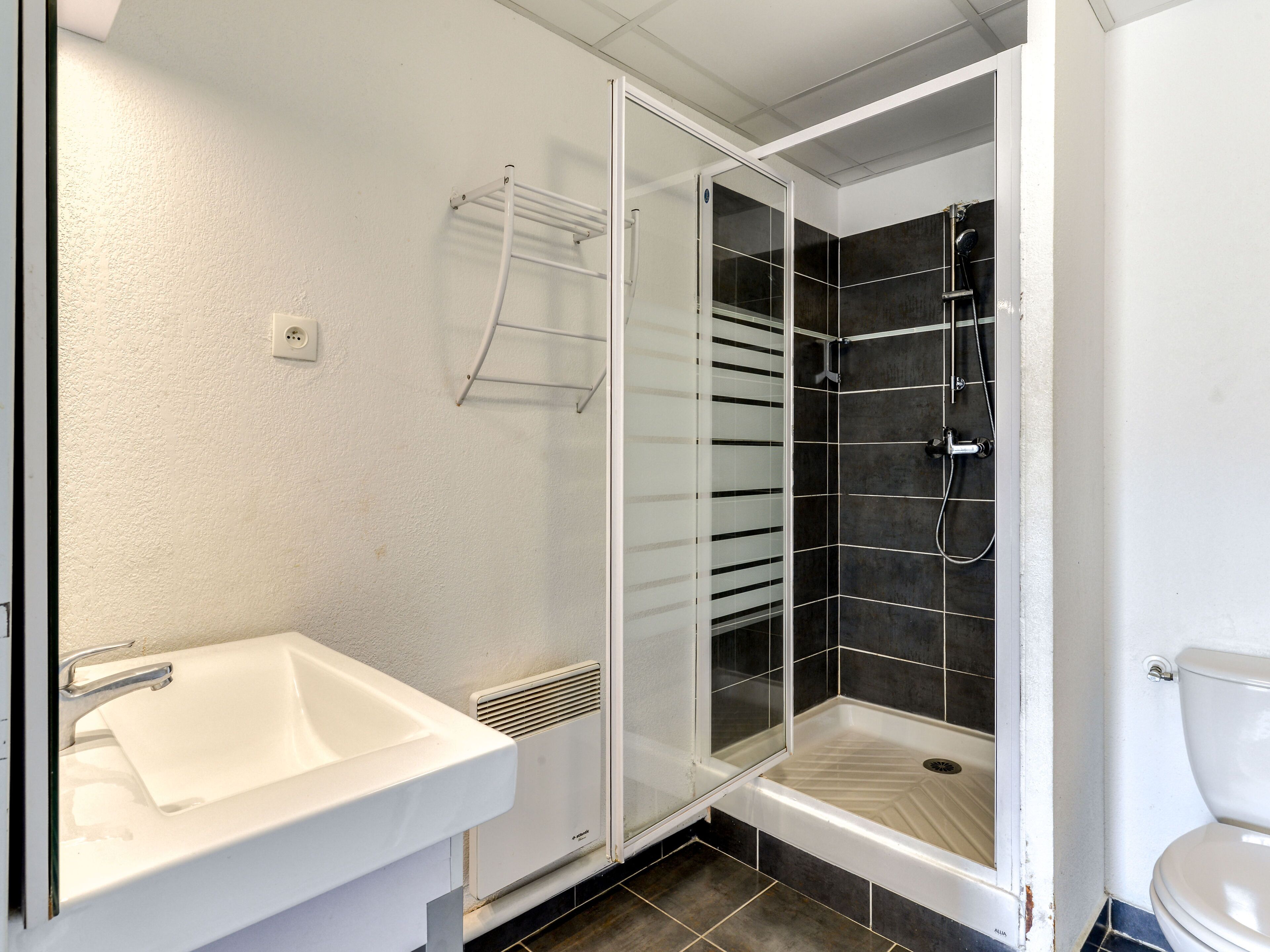 Ein Badezimmer mit einem weißen Waschbecken, einer Duschkabine aus Glas und einer Toilette.