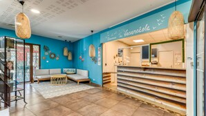 A reception area with a blue wall, a reception desk, a sofa, and hanging wicker lamps.