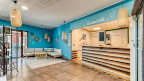 A reception area with a blue wall, a reception desk, a sofa, and hanging wicker lamps.