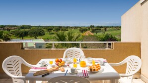 Balcón con mesa lista para el desayuno, con vista a un campo de golf.