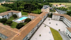 A large building with multiple wings, a swimming pool, and a tennis court.