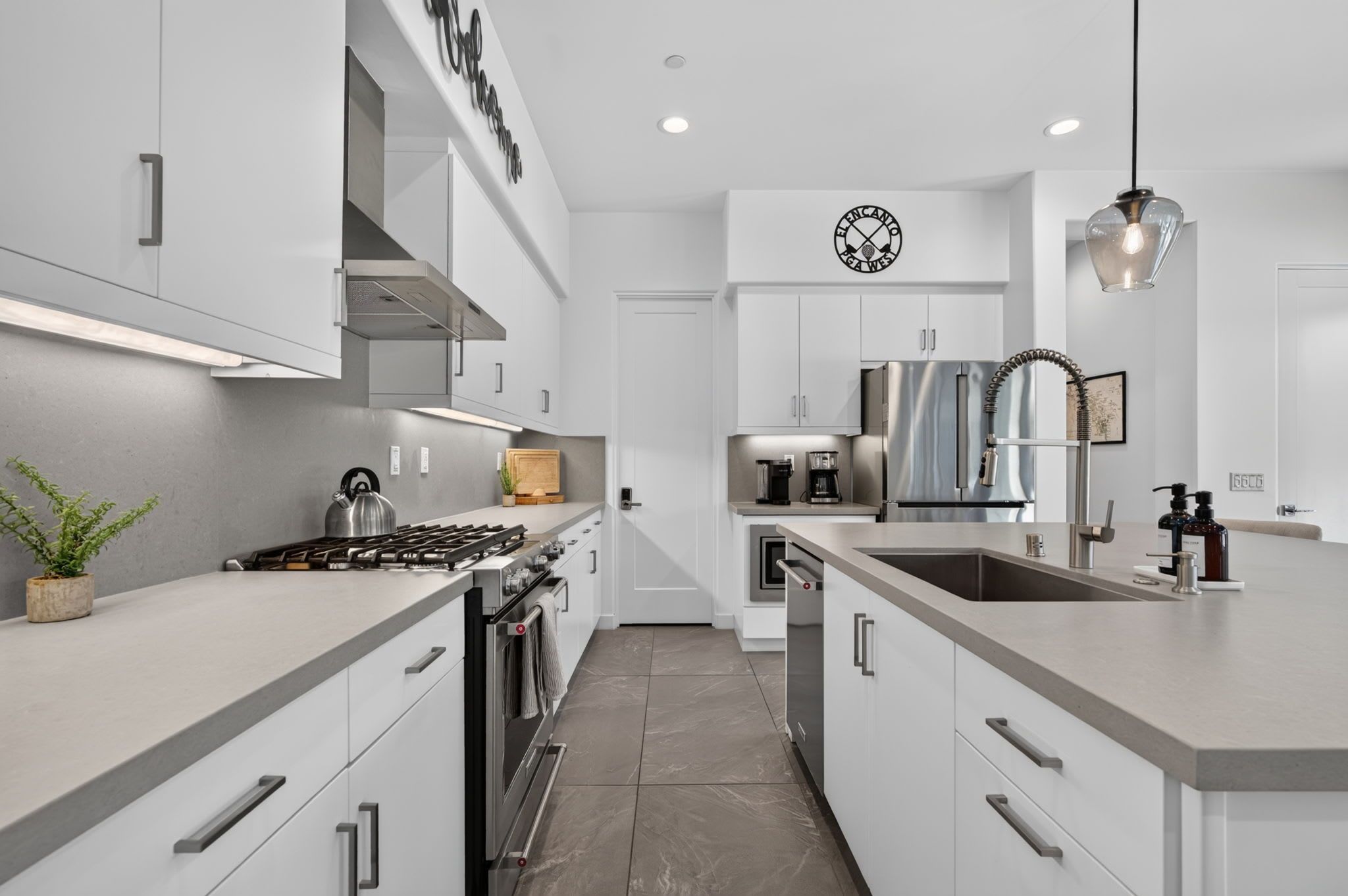 Una cocina moderna con armarios blancos, estufa de acero inoxidable y horno empotrado.