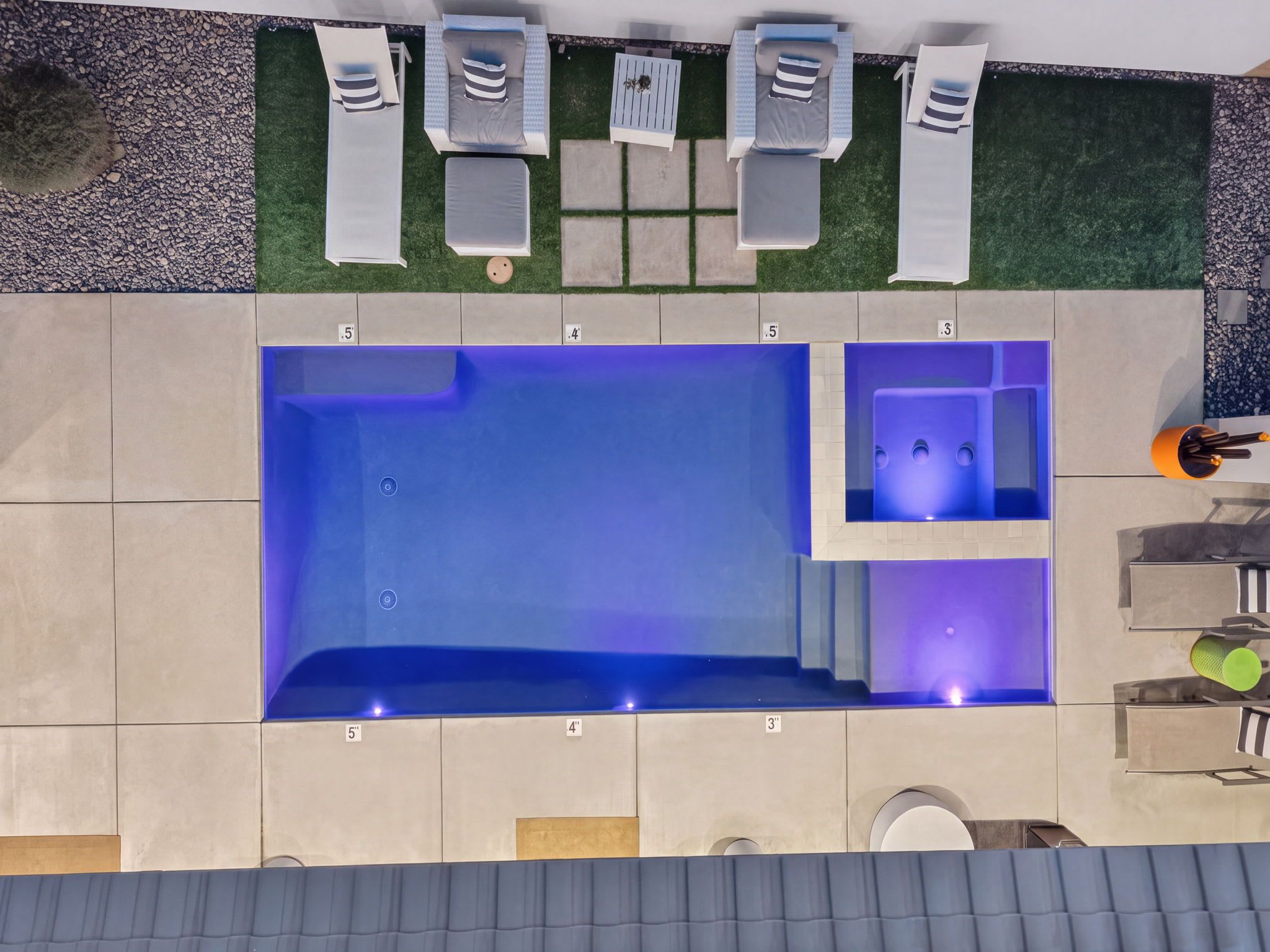 A rooftop pool area with a hot tub, lounge chairs, and a small seating area.