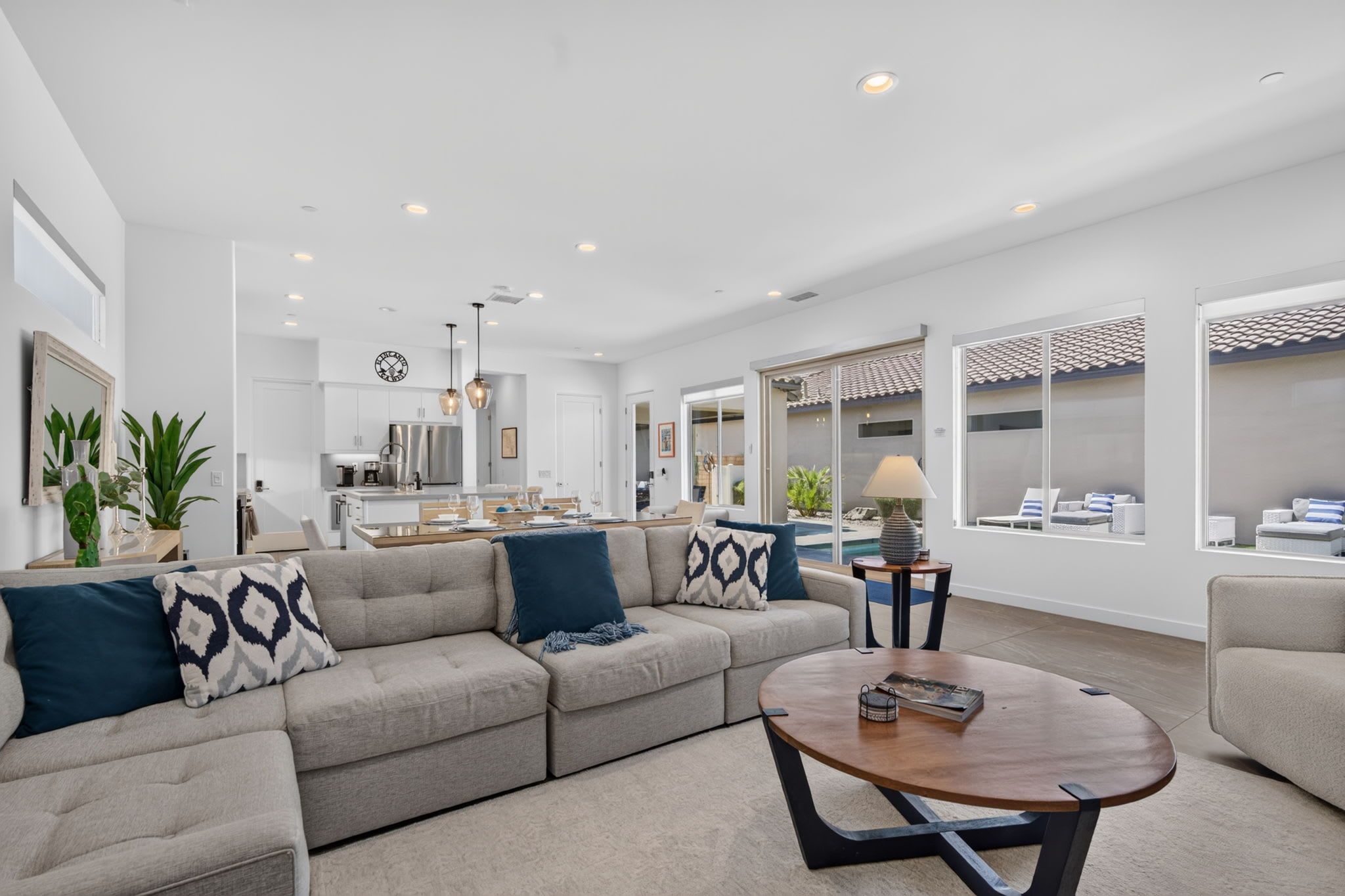 A modern living room with a sectional sofa, a round coffee table, and a dining area in the background.
