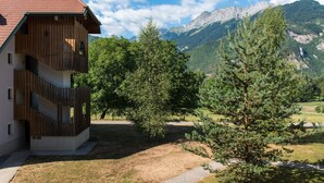 Kaksikerroksinen rakennus, jossa on puinen julkisivu ja parveke. Rakennuksen ympärillä on puita ja taustalla näkyy vuoria.