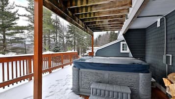 Guests can unwind in this serene outdoor space featuring a hot tub and wooden deck with a pergola.