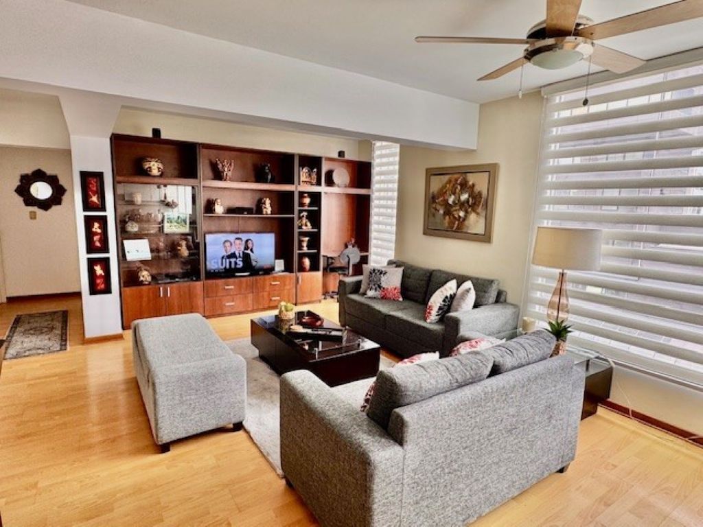 A living room with a grey sofa set, a coffee table, and a TV on a wooden cabinet.