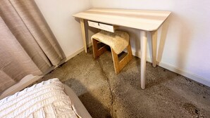 Una habitación pequeña con un escritorio de madera, un banco y una cama.
