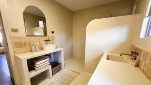 Un baño moderno con una bañera independiente, un tocador con un espejo grande y un perchero para toallas.