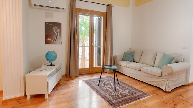 Un salon comprenant un canapé, une petite table sur laquelle repose un globe terrestre, un tapis à motifs et une porte-fenêtre coulissante.