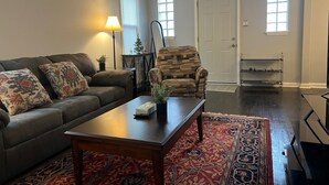 Un salon comprenant un canapé, un fauteuil, une table basse et un tapis à motifs.