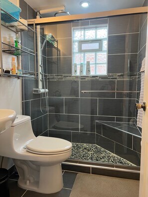 Une salle de bain moderne avec une douche, des toilettes et une fenêtre donnant sur un beau paysage.