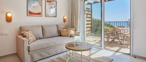 Una sala de estar moderna con un sofá, una mesa redonda de centro y un balcón con mobiliario exterior.