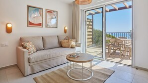 A modern living room with a sofa, a round coffee table, and a balcony with outdoor furniture.