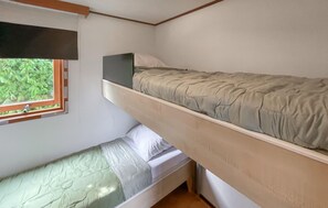 A bunk bed room with a window, a small table, and a green mattress.